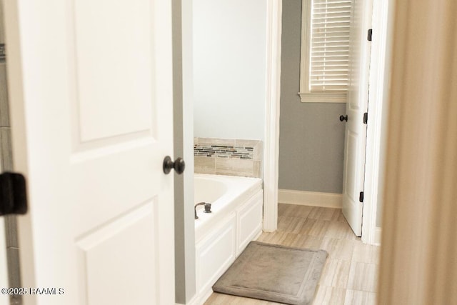 bathroom featuring a bath and baseboards