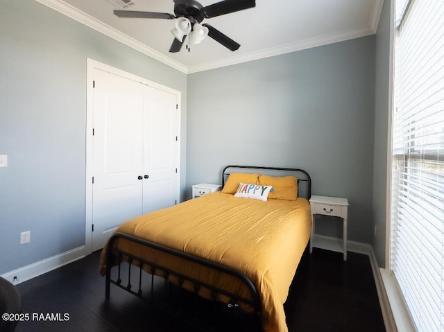 bedroom with a closet, wood finished floors, baseboards, and ornamental molding