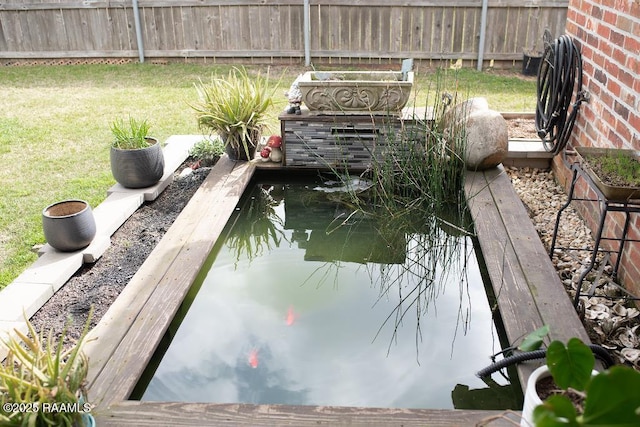 exterior space with a lawn, a small pond, and fence