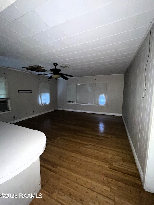 interior space with baseboards, ceiling fan, and wood finished floors