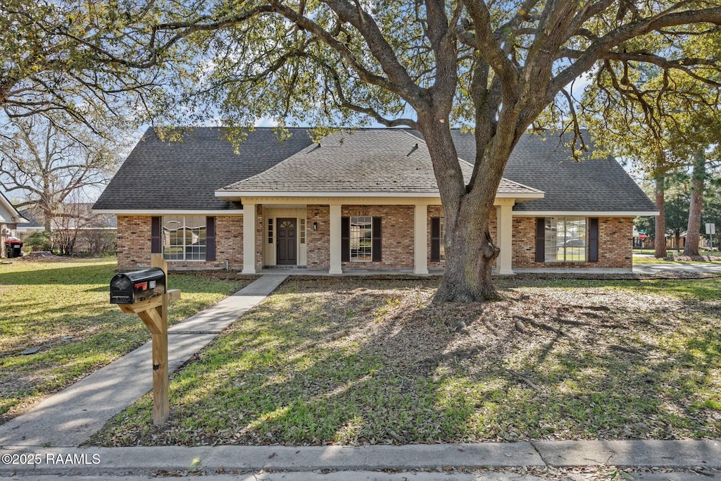 view of front of property featuring brick siding, a front lawn, and a shingled roof
