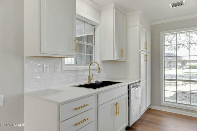 kitchen featuring visible vents, a sink, dishwasher, crown molding, and backsplash