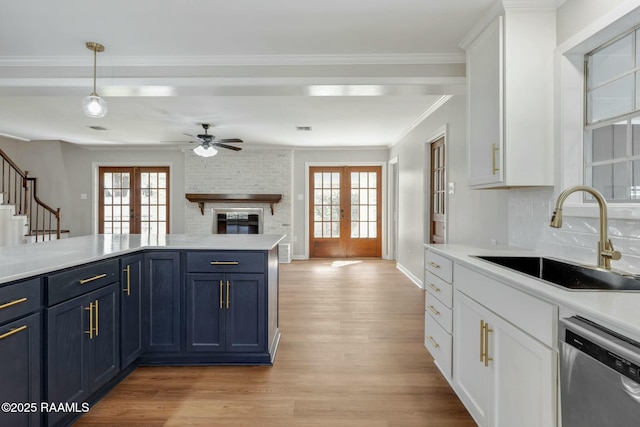 kitchen with a sink, blue cabinetry, french doors, light countertops, and dishwasher