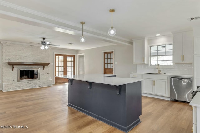 kitchen featuring visible vents, light wood-style floors, dishwasher, and white cabinetry