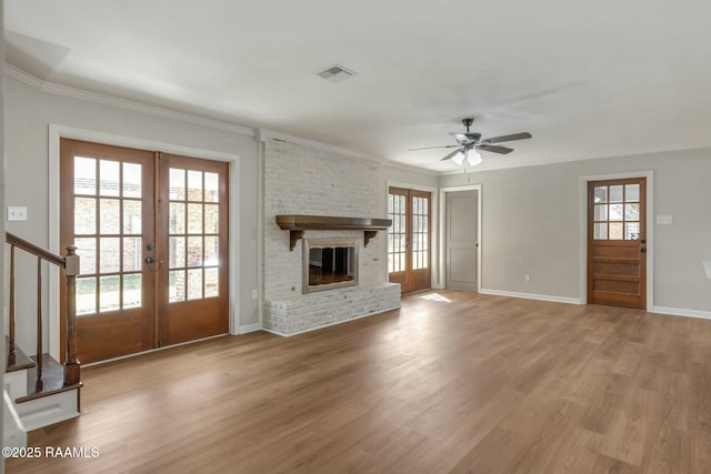 unfurnished living room featuring stairway, ornamental molding, light wood-style flooring, french doors, and a ceiling fan