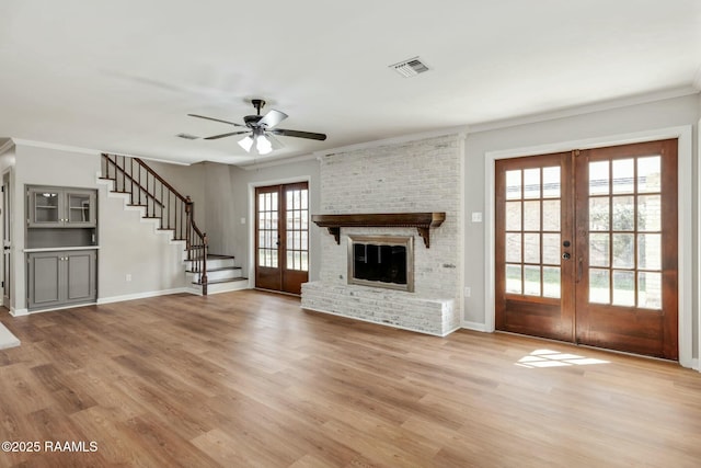 unfurnished living room with visible vents, french doors, stairway, and wood finished floors