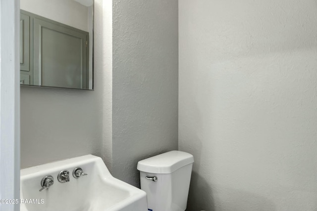 half bath featuring toilet and a textured wall