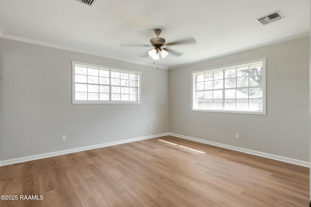 empty room featuring a ceiling fan, baseboards, visible vents, ornamental molding, and light wood-style floors