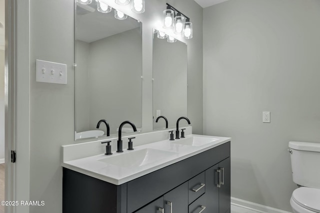 full bath with double vanity, toilet, baseboards, and a sink