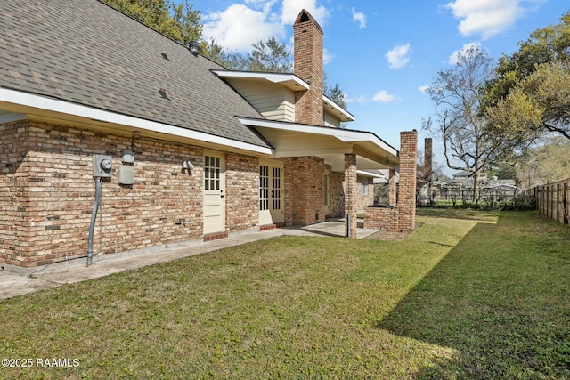 back of house featuring a lawn, a patio, a fenced backyard, roof with shingles, and a chimney