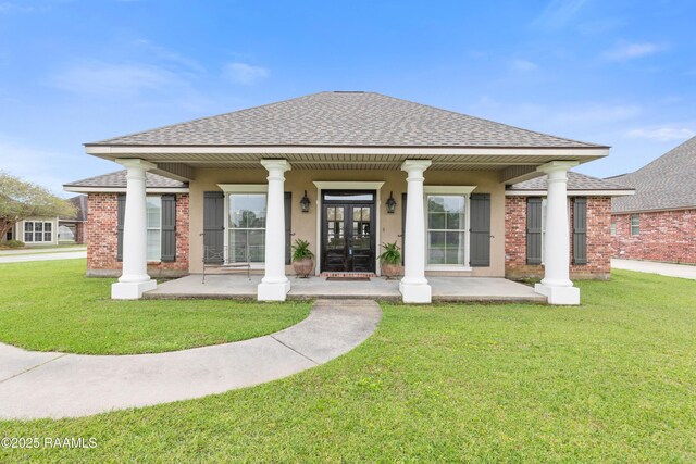 view of front facade featuring a front yard, brick siding, stucco siding, a shingled roof, and french doors