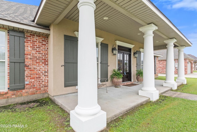 entrance to property featuring stucco siding, brick siding, a shingled roof, and a porch