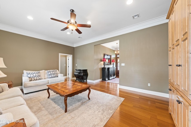 living area with crown molding, light wood-type flooring, visible vents, and a ceiling fan