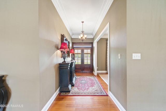 interior space with an inviting chandelier, crown molding, light wood-style floors, and baseboards