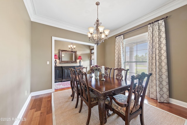 dining space featuring crown molding, baseboards, a chandelier, and wood finished floors