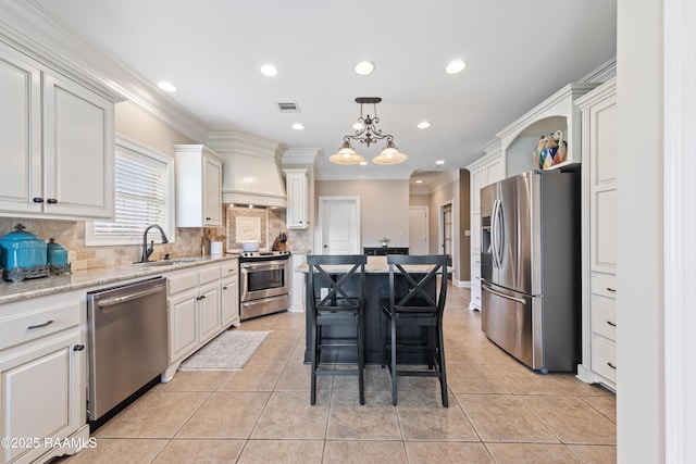 kitchen featuring light tile patterned floors, stainless steel appliances, a kitchen island, a sink, and visible vents