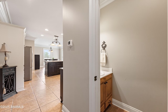 interior space with baseboards, ornamental molding, tile patterned floors, vanity, and a notable chandelier