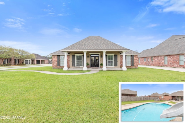 rear view of property with roof with shingles, a fenced in pool, fence, and a yard