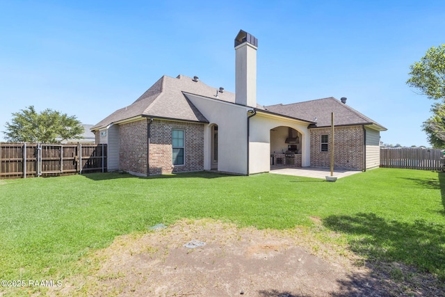 rear view of property with a fenced backyard, a chimney, brick siding, and a patio