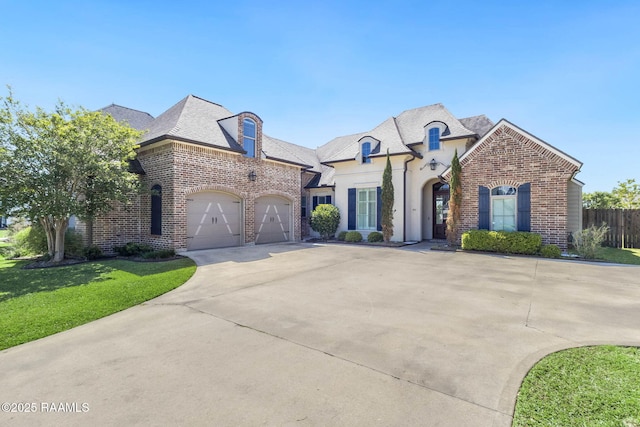 french country home featuring concrete driveway, an attached garage, brick siding, and a front yard