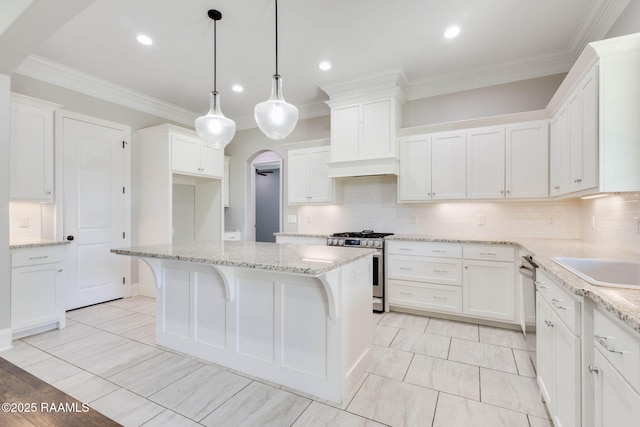 kitchen featuring a center island, arched walkways, tasteful backsplash, white cabinetry, and appliances with stainless steel finishes