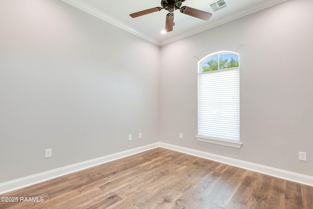 spare room with a ceiling fan, wood finished floors, baseboards, ornamental molding, and visible vents