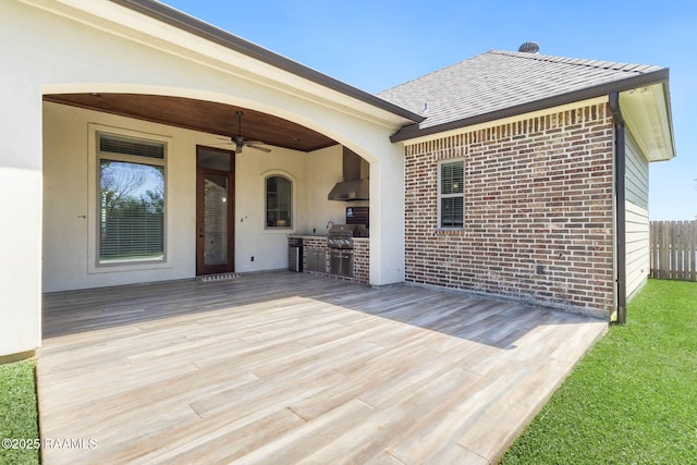 deck with fence, a ceiling fan, and exterior kitchen