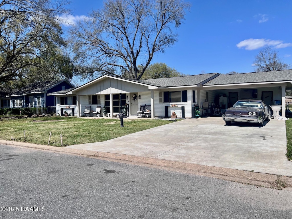 ranch-style house with driveway, an attached carport, and a front lawn