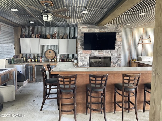 3713 Vidrine Rd, Ville Platte, LA 70586 - kitchen with white cabinetry, a ceiling fan, a stone fireplace, a breakfast bar area, and light countertops