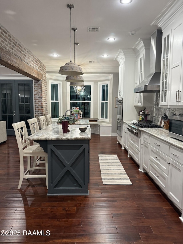 3713 Vidrine Rd, Ville Platte, LA 70586 - kitchen featuring wall chimney range hood, a center island, white cabinetry, stainless steel appliances, and ornamental molding