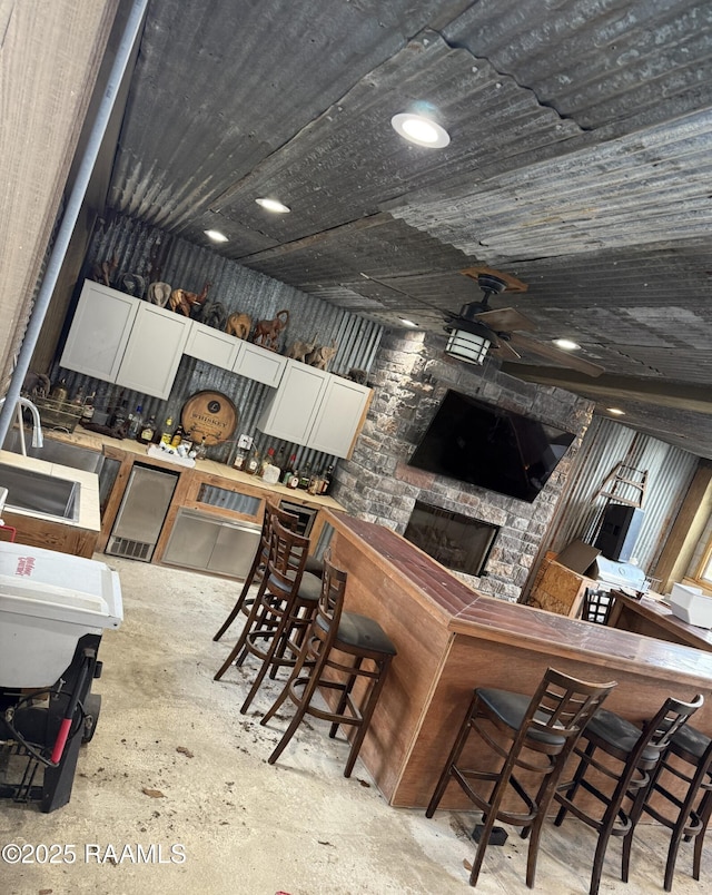 3713 Vidrine Rd, Ville Platte, LA 70586 - kitchen with white cabinets, a fireplace, concrete floors, and a ceiling fan