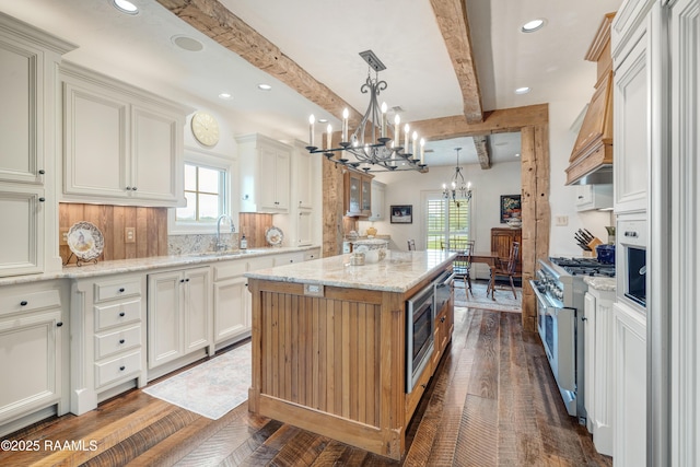 kitchen with a wealth of natural light, a notable chandelier, appliances with stainless steel finishes, and a sink