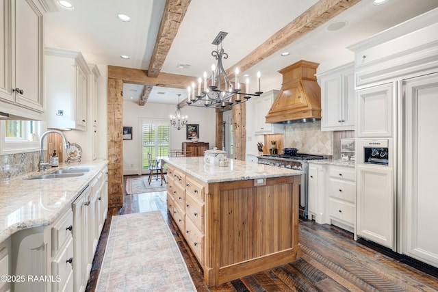 kitchen with a kitchen island, custom exhaust hood, a sink, high quality appliances, and a chandelier