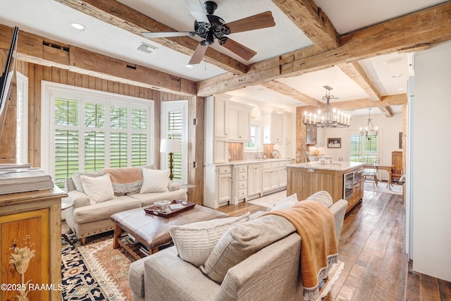 living area with visible vents, beamed ceiling, recessed lighting, light wood-style flooring, and ceiling fan with notable chandelier