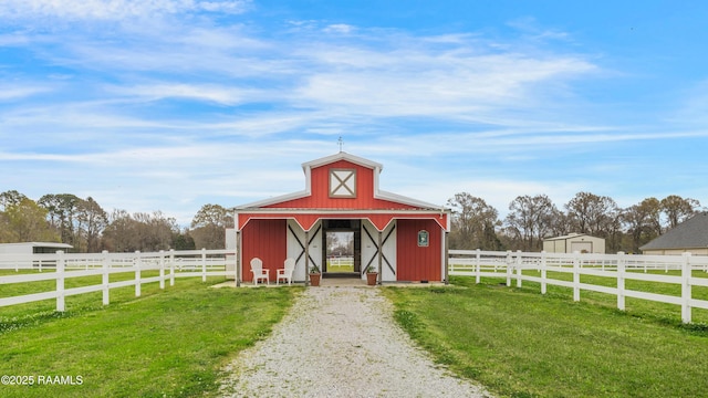 view of barn featuring a lawn and fence