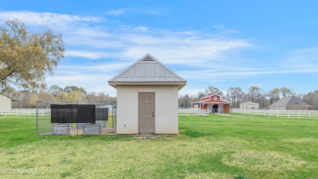 view of outbuilding with a rural view, an outdoor structure, and fence