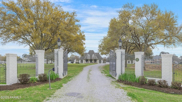 view of street with gravel driveway, a gate, street lighting, and a gated entry