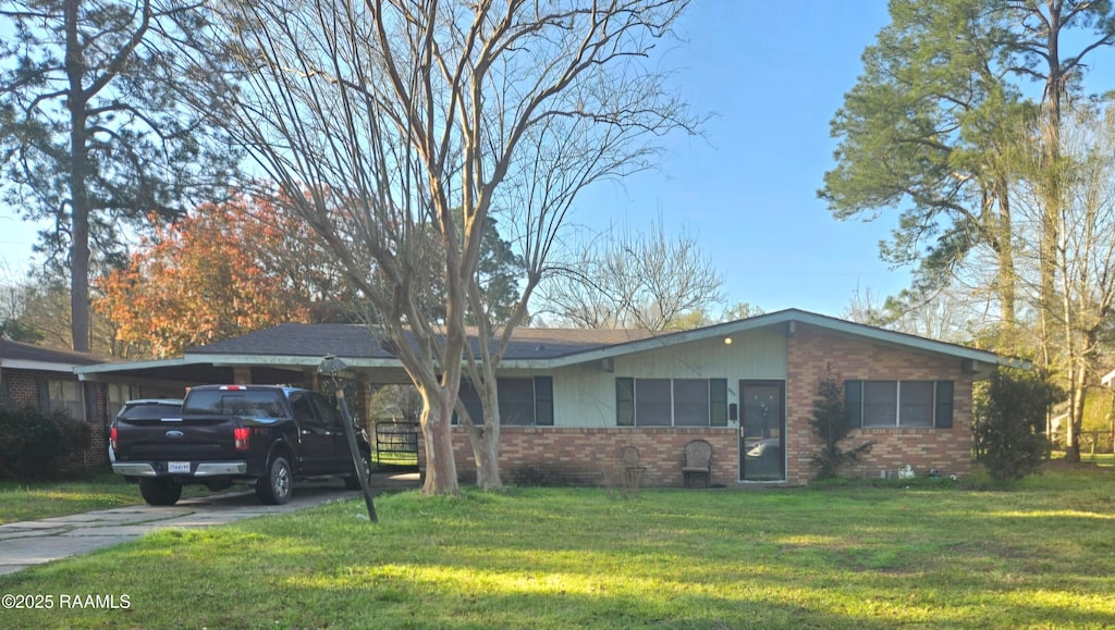 view of front facade with an attached carport, concrete driveway, brick siding, and a front yard