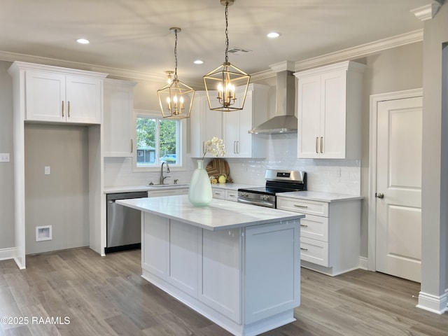 kitchen featuring wall chimney exhaust hood, a sink, white cabinetry, a chandelier, and appliances with stainless steel finishes