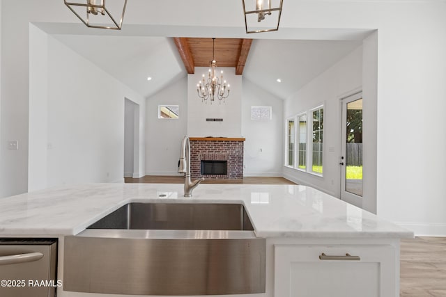 303 Canary Palm Way, Youngsville, LA 70592 - kitchen featuring a chandelier, open floor plan, light stone counters, a brick fireplace, and pendant lighting
