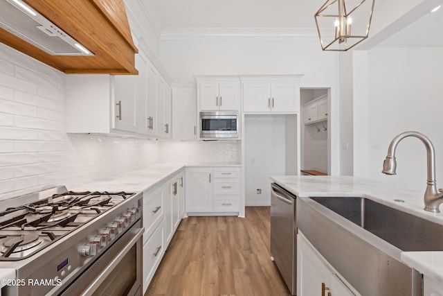 303 Canary Palm Way, Youngsville, LA 70592 - kitchen with stainless steel appliances, ventilation hood, light stone counters, white cabinets, and ornamental molding
