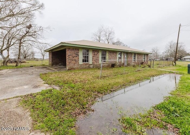 single story home with brick siding, a front lawn, an attached carport, and driveway
