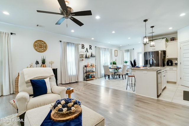 living room with light wood-style floors, recessed lighting, visible vents, and ceiling fan