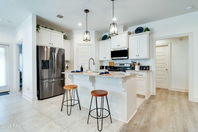 kitchen with a breakfast bar, visible vents, white cabinetry, and stainless steel appliances