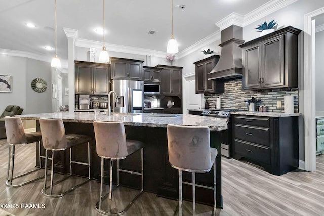 205 Lo Saab Cv, Lafayette, LA 70506 - kitchen with appliances with stainless steel finishes, custom exhaust hood, a kitchen bar, light stone counters, and backsplash