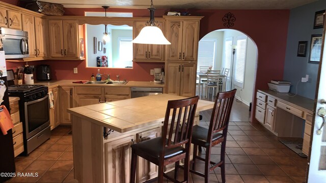 178 Wild Iris Dr, Evangeline, LA 70537 - kitchen featuring dark tile patterned floors, tile countertops, arched walkways, stainless steel appliances, and a sink