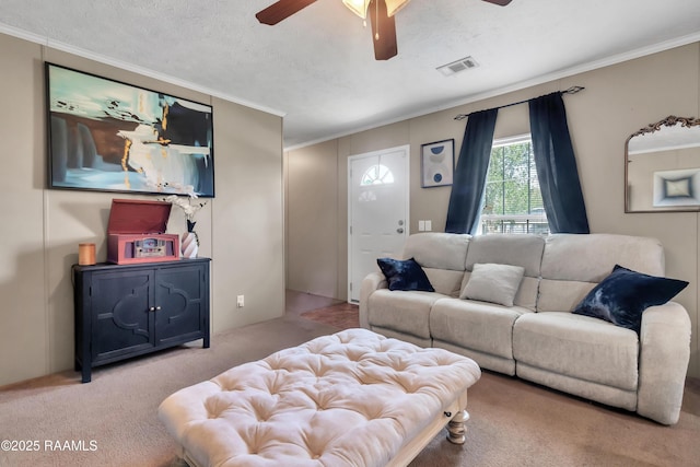 living area with visible vents, ceiling fan, carpet floors, and crown molding