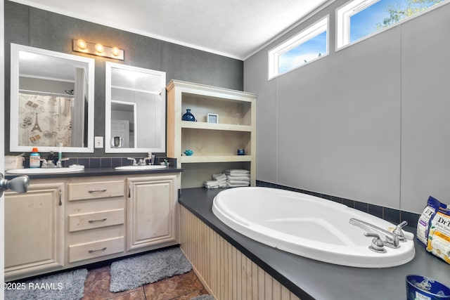 bathroom with double vanity, stone finish flooring, ornamental molding, a sink, and a garden tub