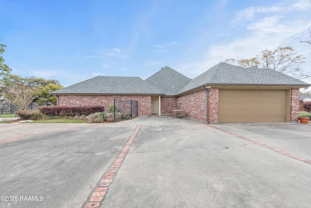 ranch-style house featuring driveway, fence, roof with shingles, an attached garage, and brick siding