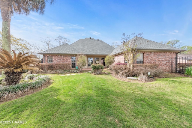 back of property with a lawn, brick siding, and a shingled roof
